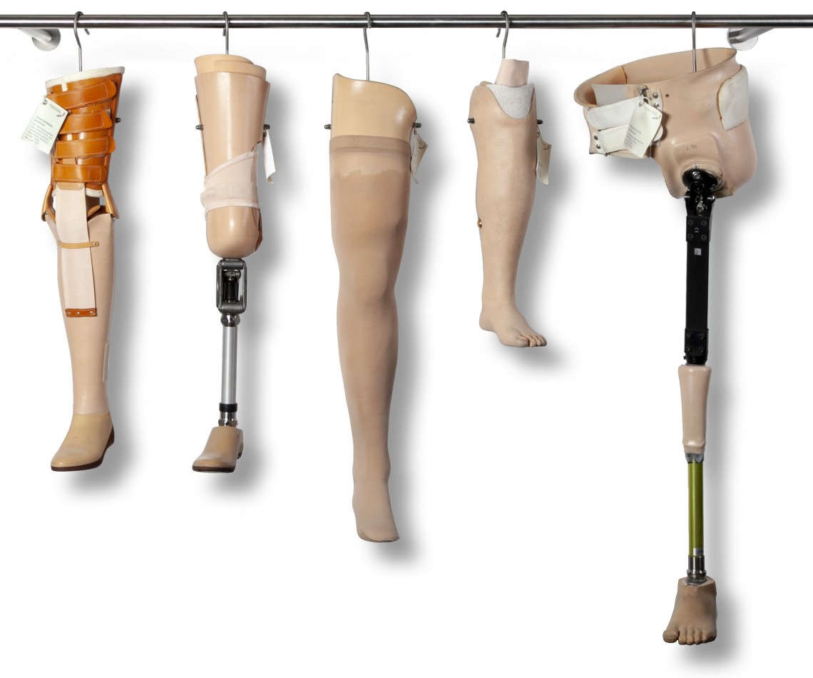 Fünf Beinprothesen aus verschiedenen Epochen die in der Sammlung  wie Designer-Kleidungsstücke an einer Kleiderstange hängend ausgestellt sind