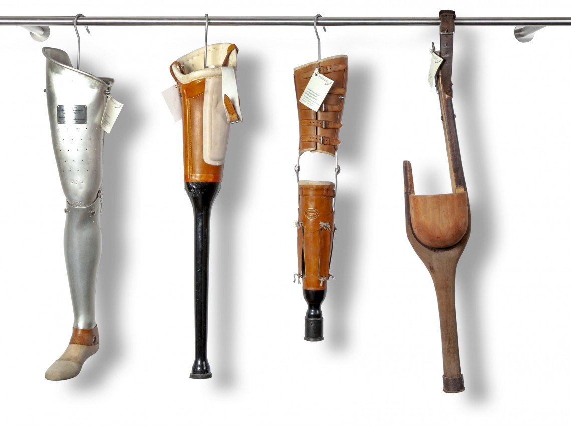 Vier Beinprothesen die in der Sammlung  wie Designer-Kleidungsstücke mit Kleiderbügel an einer Kleiderstange hängend ausgestellt sind